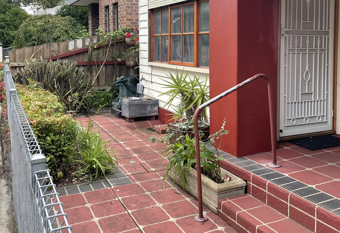 A clean paved front yard garden with trimmed perimeter plants