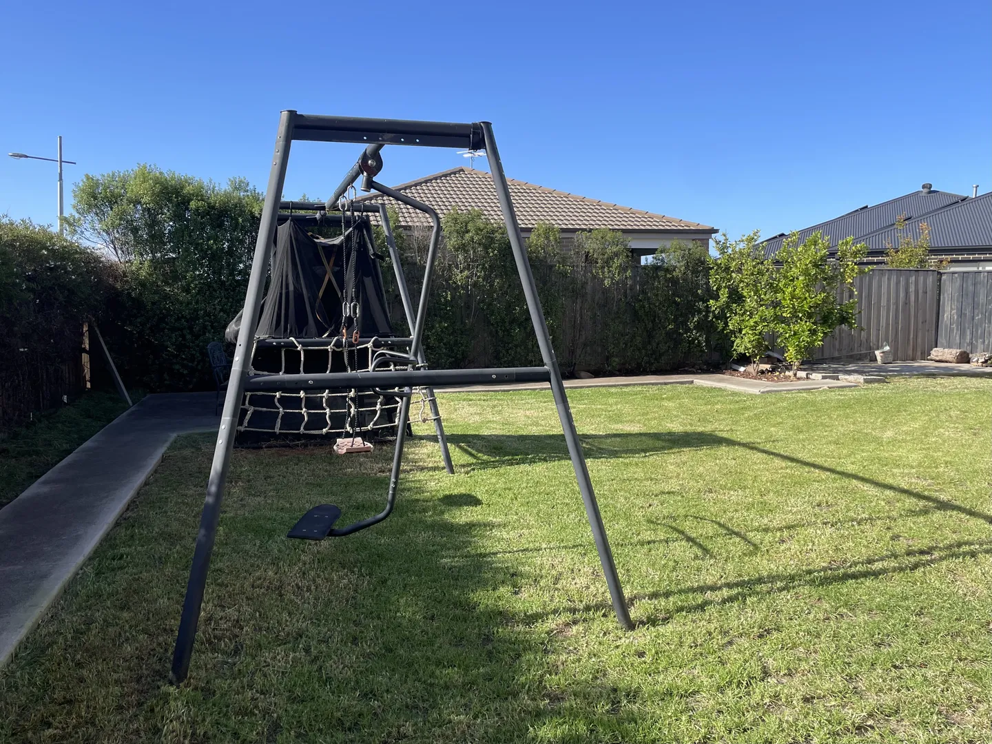 A spacious freshly mowed green lawn in a backyard, with a swing set showing