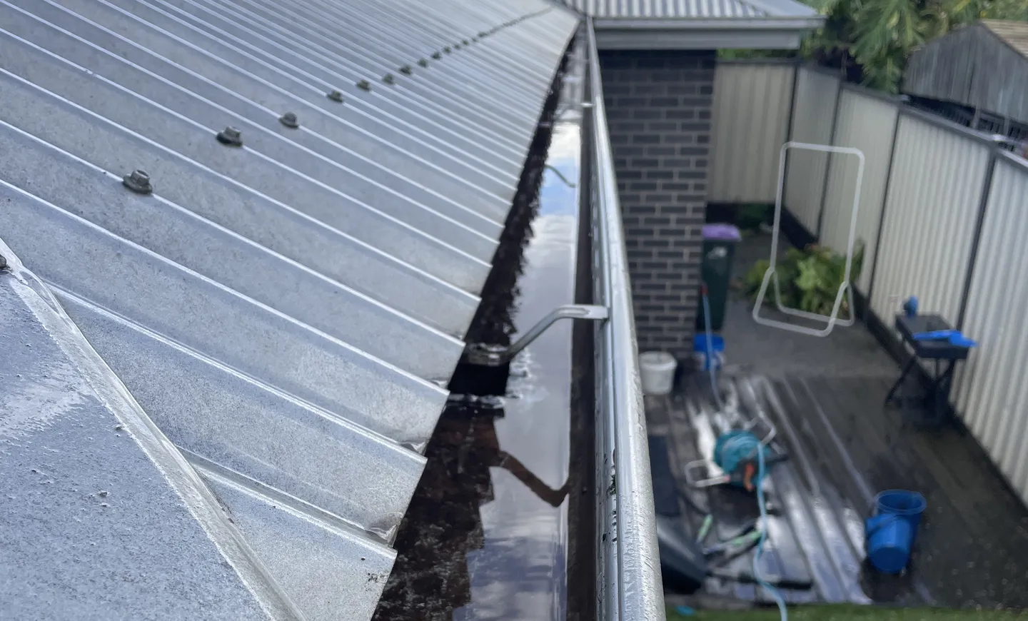 A roof gutter, cleared of all leaves, dirt and other material, with running, reflective water after cleanout