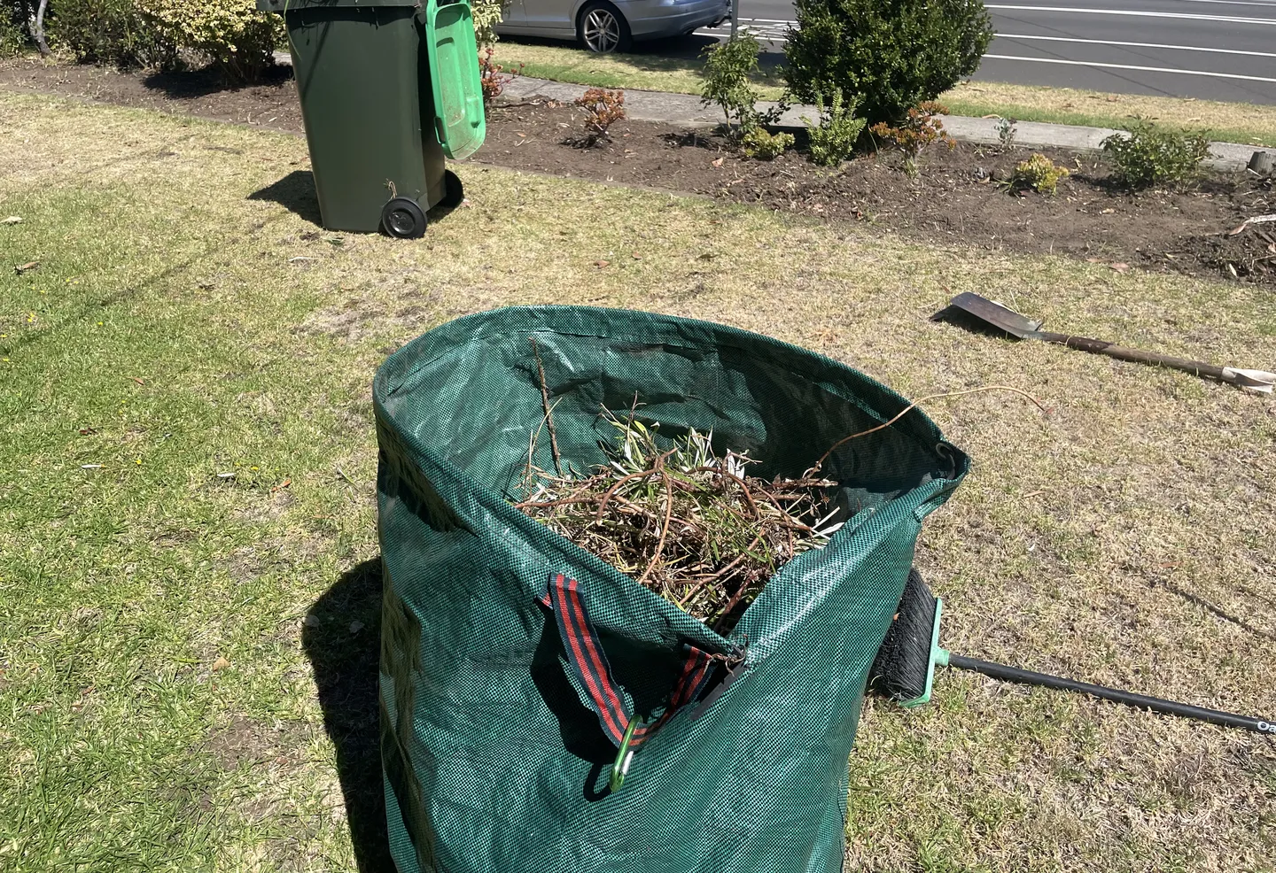 Green collapsible garden waste bag filled with twigs and other green waste during yard cleanup